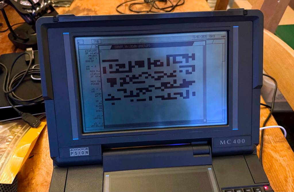 A close-up of a Psion MC400 handheld computer displaying a code editing screen with a blocky text layout.